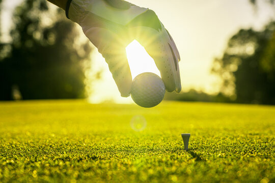 Closeup of golfer wearing glove placing golf ball on a tee at golf course
