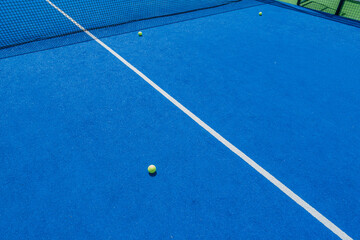 blue paddle tennis court with two balls near the net