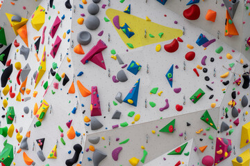 Street artificial rock climbing wall close-up view various colored grips. Colorful footholds for...