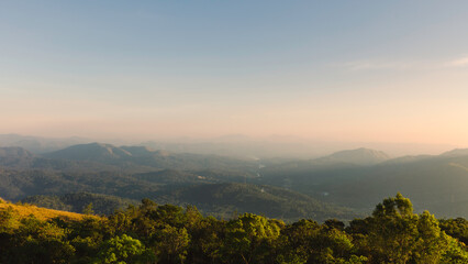 Cardamom hills under clear sky with mist on horizon at sunset in Thekkady, India.