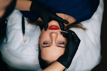 Master do permanent makeup lips procedure of girl - obrazy, fototapety, plakaty