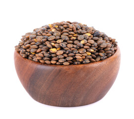 French lentils in wooden bowl, isolated on white background. Dry puy lentil grains pile.