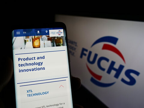 Stuttgart, Germany - 05-21-2022: Person holding cellphone with webpage of German lubricants company Fuchs Petrolub SE on screen in front of logo. Focus on center of phone display.