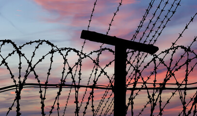 Сontour of barbed wire on the background of the sunset orange sky