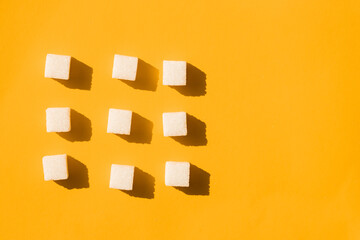 Fototapeta na wymiar Pointer of white sugar cubes on yellow background