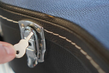 Macro shot of a black leather guitar case and detail of a vintage closure with an instrument-shaped...