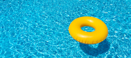 Yellow inflatable ring floating in swimming pool. Vacation concept with copy space - obrazy, fototapety, plakaty