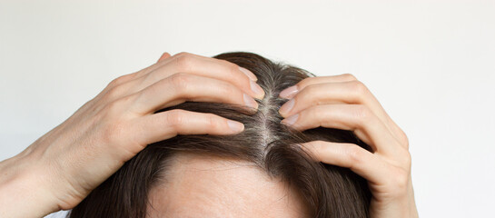 Fototapeta premium A middle-aged woman shows gray hair roots.