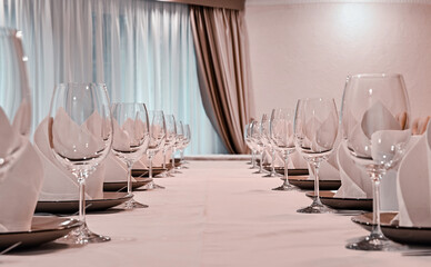 empty wine glasses on a table with white tablecloths. serving in a restaurant. window with curtains in the background. selective focus.