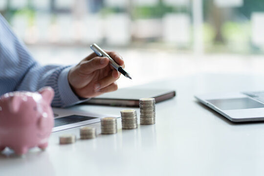 Businessman Holding A Pen Pointing A Pile Of Coins Good Piggy Bank And Investment Ideas Or Good Savings Templates Copy Space For Financial Planning Text Financial Analysis For Corporate Growth