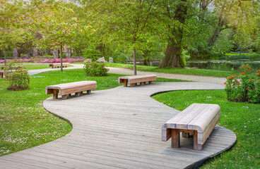Wooden garden bench in fresh green spring park	