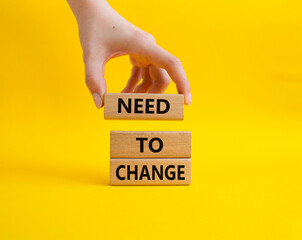 Need to change symbol. Concept words 'Need to change' on wooden blocks. Beautiful yellow background. Businessman hand. Business and Need to change concept. Copy space.