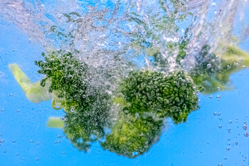 Falling fresh broccoli into water with splash and bubbles. Selective focus, clos up image.