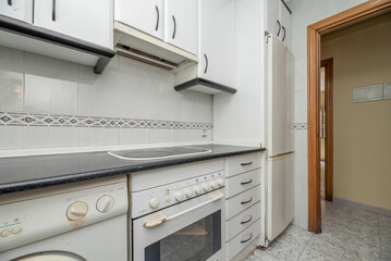 Apartment kitchen with white cabinets with matching drawers and doors and white appliances