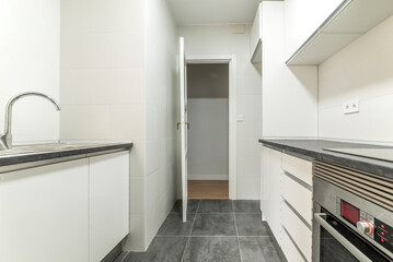 Simple apartment kitchen with newly installed white cabinets, gray countertop and stainless steel appliances