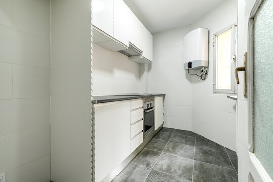 Kitchen With Newly Installed Cabinets And Drawers In A Simple Apartment With Gray Tile Floors, Natural Gas Water Heater