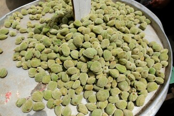 A pile of raw green almonds on metal plate on stall in Amman market, Jordan
