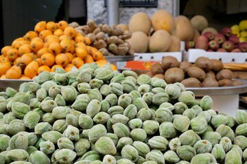 A pile of raw green almonds on a market stall. Colorful exotic fruits in background in Amman market, Jordan