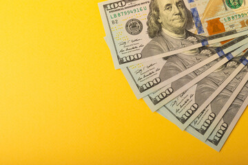 Money, US hundred dollar banknotes background on yellow background. Money is scattered on the table. Concepts of finance and economy. Money accumulation concept. Saving currency. Investments. 