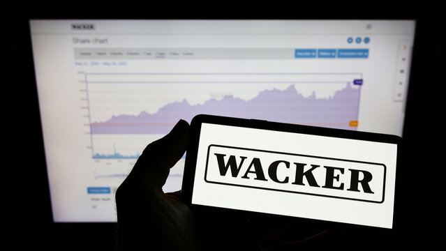 Stuttgart, Germany - 05-21-2022: Person holding mobile phone with logo of German chemical company Wacker Chemie AG on screen in front of business web page. Focus on phone display.