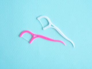 Dental floss with plastic toothpick white and pink on blue with space for text. Dental concept