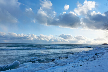 Snow covered ground near a cold blue lake