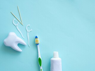 Dental concept of oral hygiene. Dental floss with plastic toothpick, big white tooth, toothpaste...