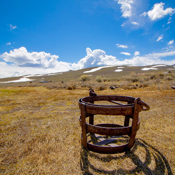 historical mining basket in a landscape setting with a grass field and blue sky with clouds