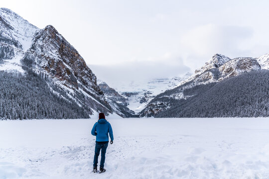 Tourist taking photos in winter season at Lake Louise, Alberta, Canada. Man in blue jacket. 