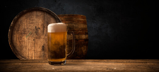 Beer. Still life with Vintage beer barrel and glass light beer. Fresh amber beer concept. Green hop...
