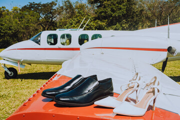 Groom and bride shoes on the wings of an airplane in the sunlight