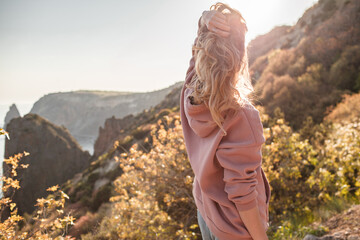 Naklejka premium Beautiful woman dressed jeans and hoody walking in the nature against background sea and nountains