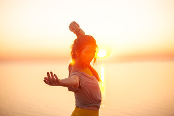 Young woman engaged in yoga in nature with view and warm light of sunset, makes poses enjoy the meditation, balance and sunrise