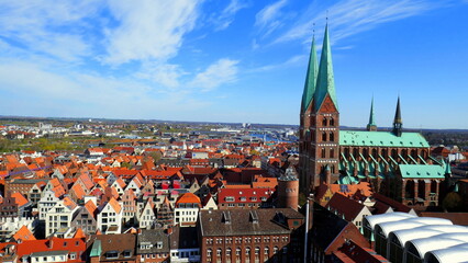 Naklejka na ściany i meble Blick vom Turm der Kirche St. Petri auf Marienkirche in Lübeck mit roten Dächern unter blauem Himmel