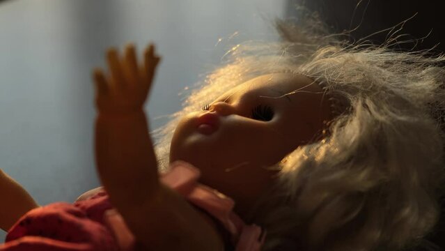 The doll lies on the floor in the room at sunset, close-up