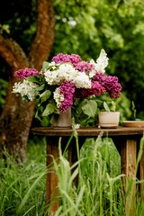 Bouquet of white and purple lilac flowers on a wooden table. Summer outdoor recreation, warm weather.
