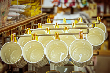 Coffee cups with golden handles hang from racks in store - Selective foucs.