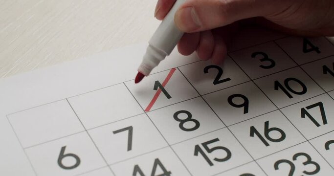 Man's hand Write down the 1th day on the paper calendar using a red pen. Very important date in the calendar. Signing a day on a calendar. Calendar 1th date of the month cut.