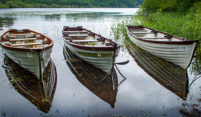 Three boats floating on the peaceful lake in a cloudy day.