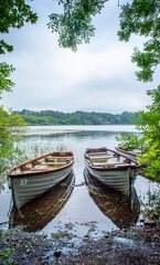 Two boats floating on the peaceful lake in a cloudy day.