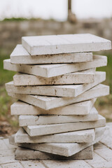 Lots of old white stone tiles stacked outdoors in a row for renovation.