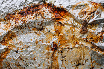 Background, texture, top view of dirty, greased, oil after cooking meat dish, crumpled foil. Photograph of food preparation.
