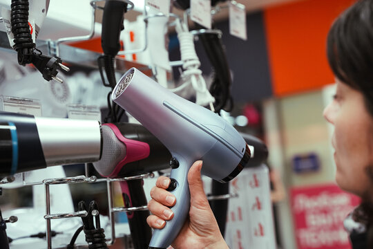 middle-aged woman chooses a hair dryer in a home appliance store