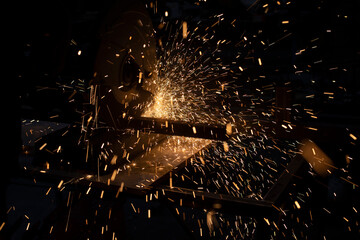 Lots of sparks from cutting metal in dark. Lights fly in different directions. Industrial...
