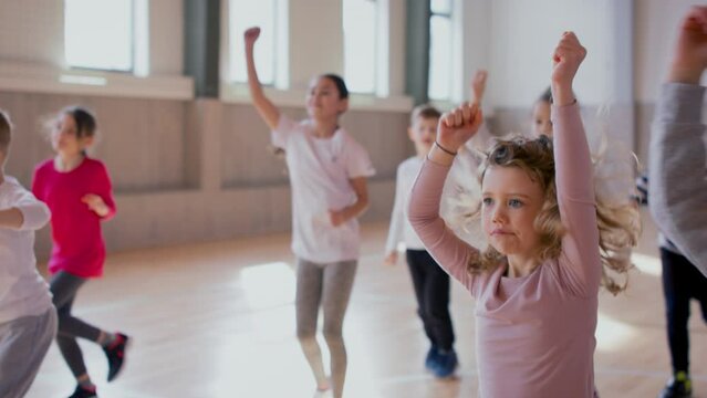 Group of elementary students exercising during class at school gym.