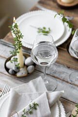 Rustic zero waste wedding decor with natural elements. Wooden table, candles, linen napkins, branches with green leaves. Eco-friendly decoration for the special dinner. Romantic and cozy place