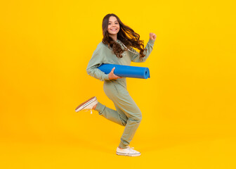 Fototapeta na wymiar Girl teenager in tracksuit. Happy cute child in a yellow sports suit on a yellow background. Run and jump. Sportswear advertising concept.