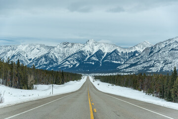 Road trip views in northern Canada during the start of winter with incredible snow capped mountains in the distance. 