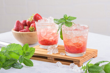 Cold summer strawberry cocktail mojito, margarita, daiquiri. Two glasses with fresh strawberry soda drink with ice cubes and mint leaves on white background. Iced strawberry lemonade, close up