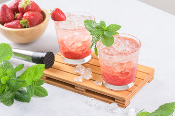 Cold summer strawberry iced cocktail mojito, margarita, daiquiri in two glasses with mint leaves on light background